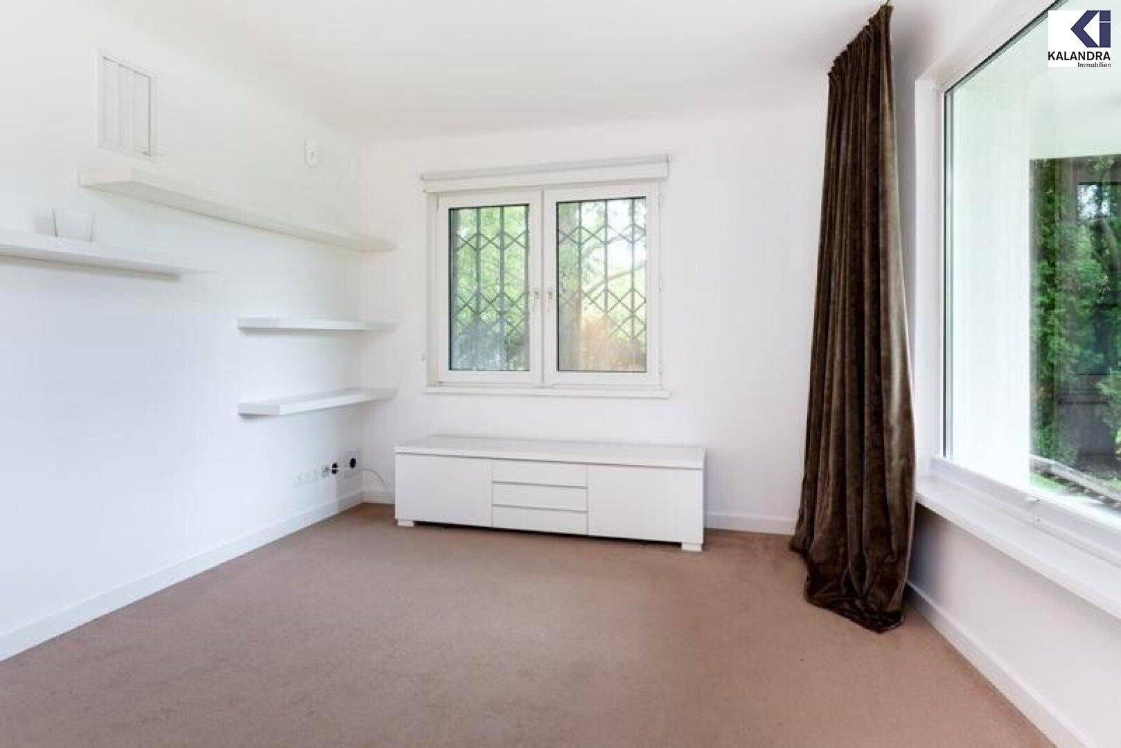 Helles Schlafzimmer mit Teppichboden, Regalen und Zugang zum Garten.