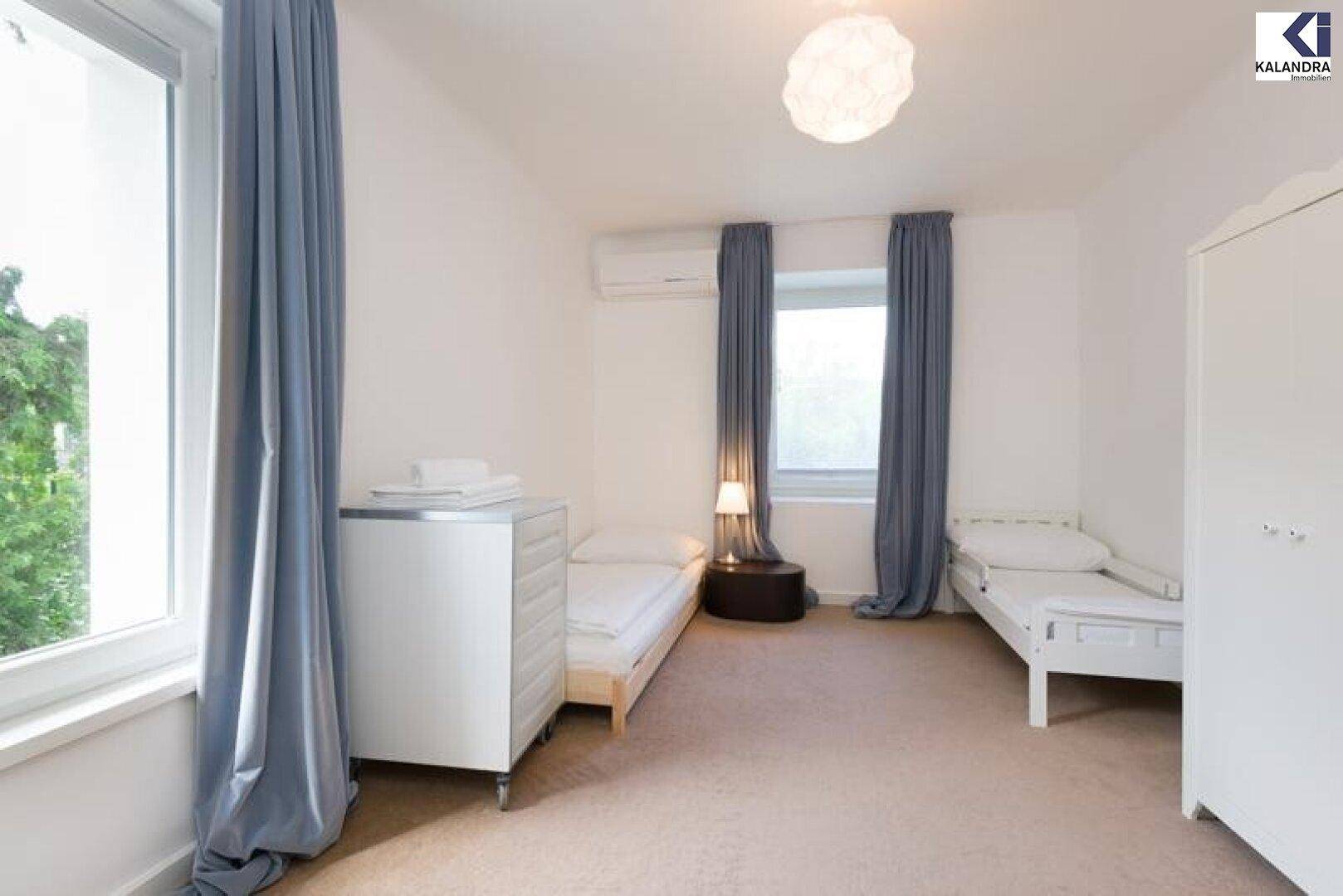 Helles Schlafzimmer mit zwei Einzelbetten, Teppichboden und Klimaanlage.