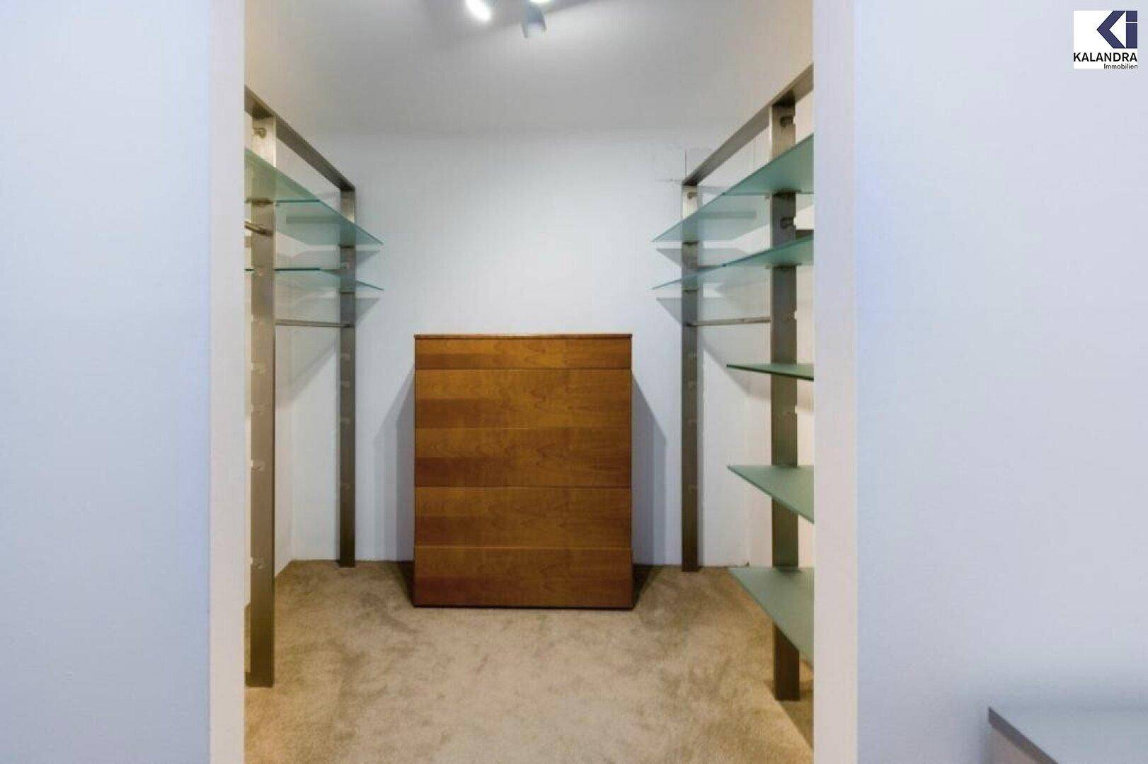 Begehbarer Kleiderschrank mit Regalen und Kommode.