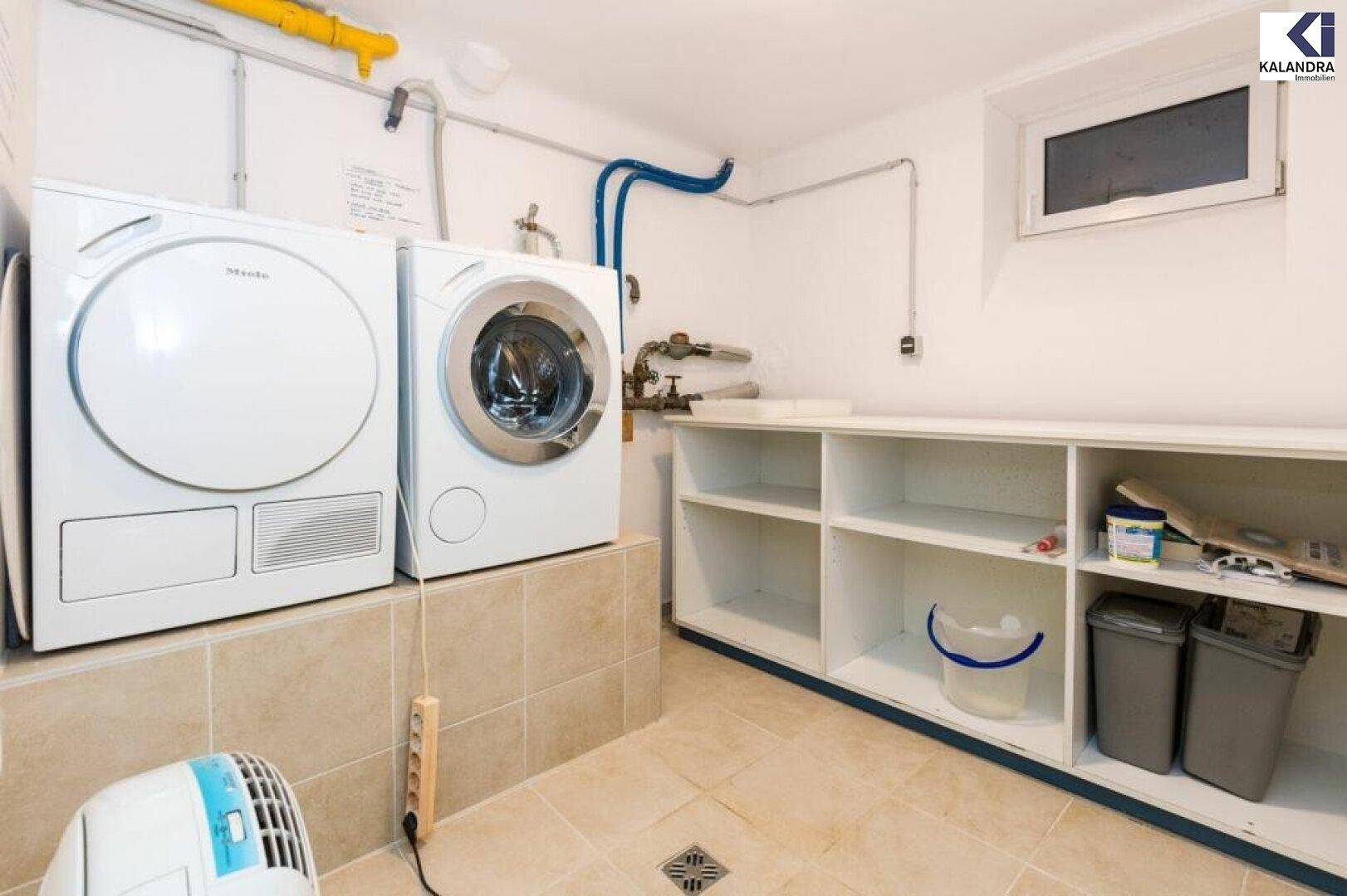 Praktischer Hauswirtschaftsraum mit Waschmaschine, Trockner und Regalen.
