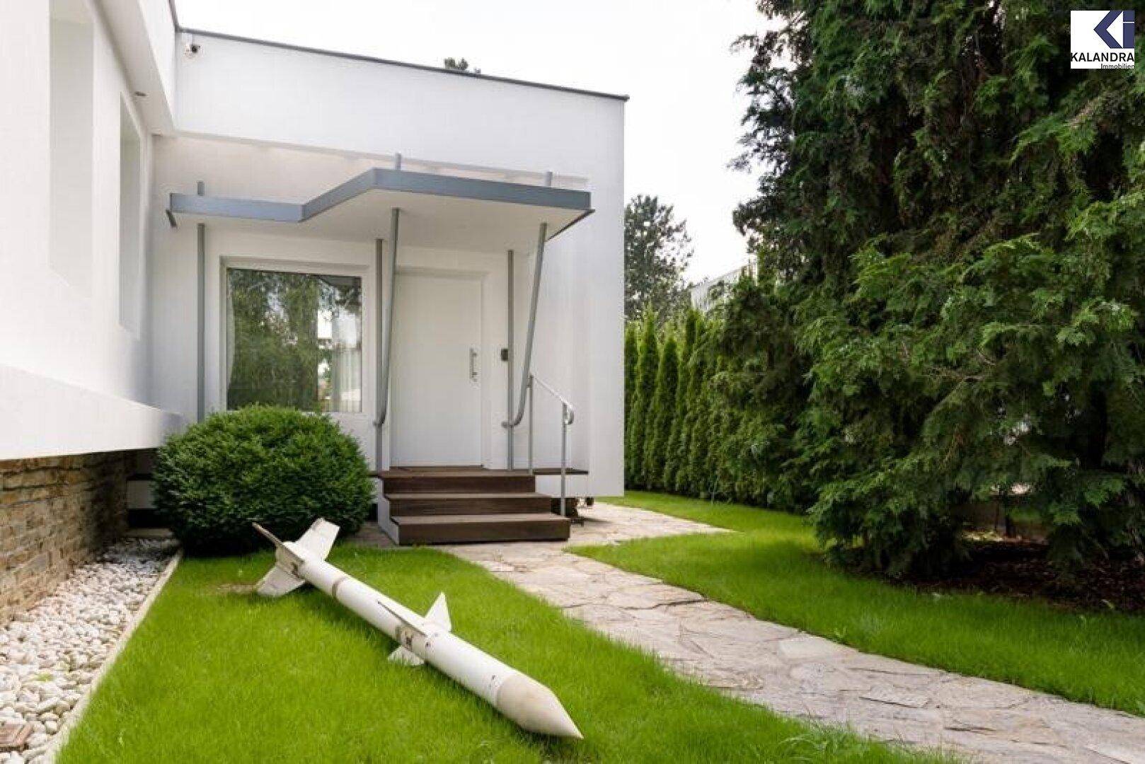 Eingangsbereich des Hauses mit Vordach, Treppe und gepflegtem Vorgarten.