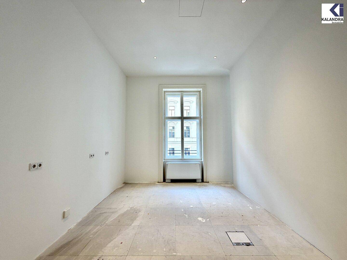 Kleiner, heller Büroraum mit einem großen Fenster und unfertigem Boden, ideal für ein Einzelbüro.