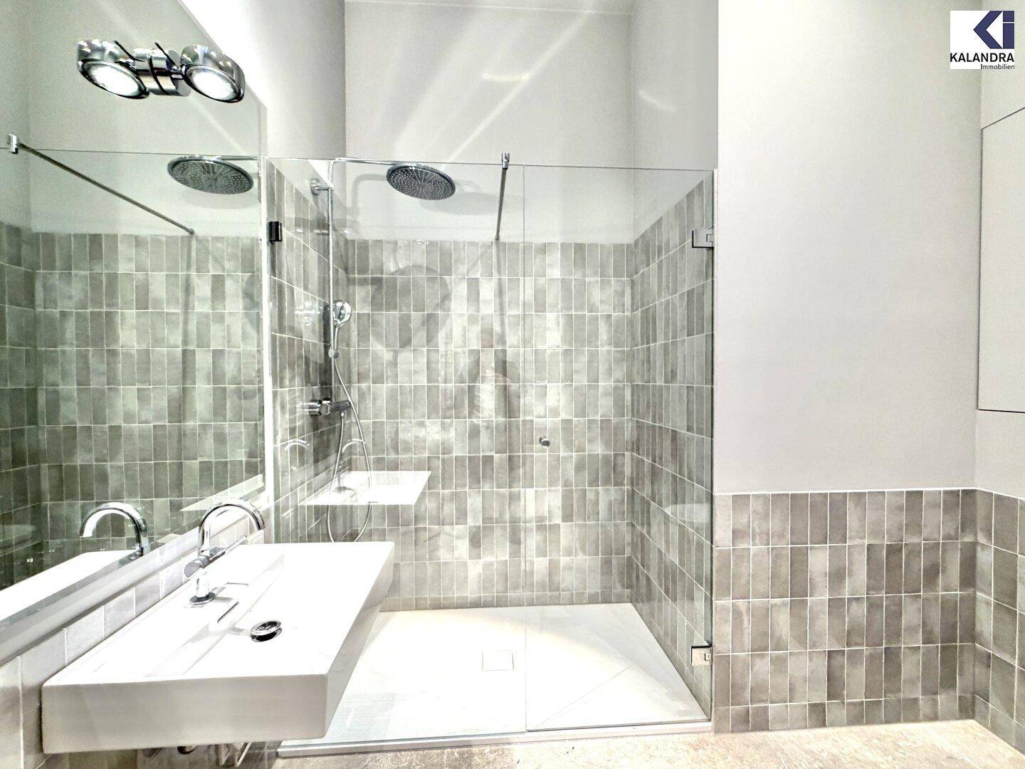Modernes Badezimmer mit begehbarer Dusche, eleganten Fliesen und stilvollem Waschbecken auf Ablage.