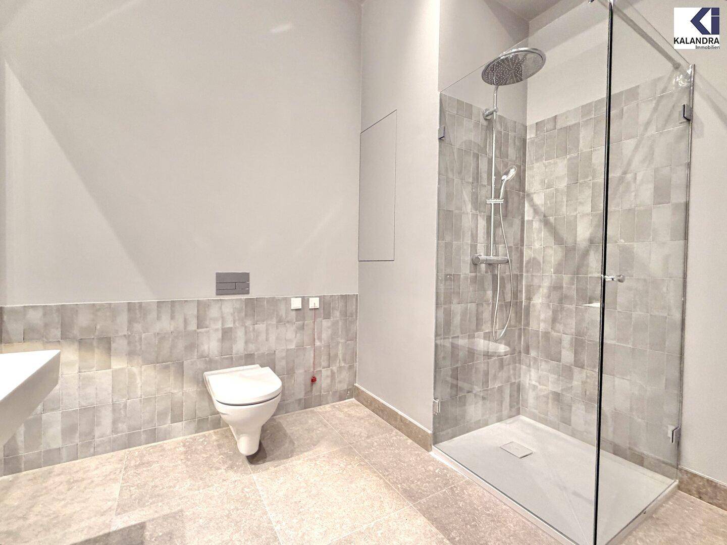 Modernes Badezimmer mit begehbarer Dusche, Wand-WC und grauen Fliesen.