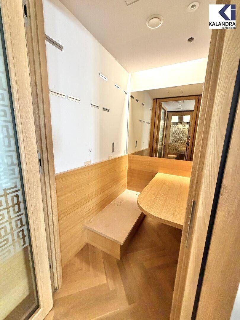 Kleiner, holzverkleideter Arbeitsbereich oder Telefonzelle mit Sitzbank und Tisch, ideal für konzentriertes Arbeiten.