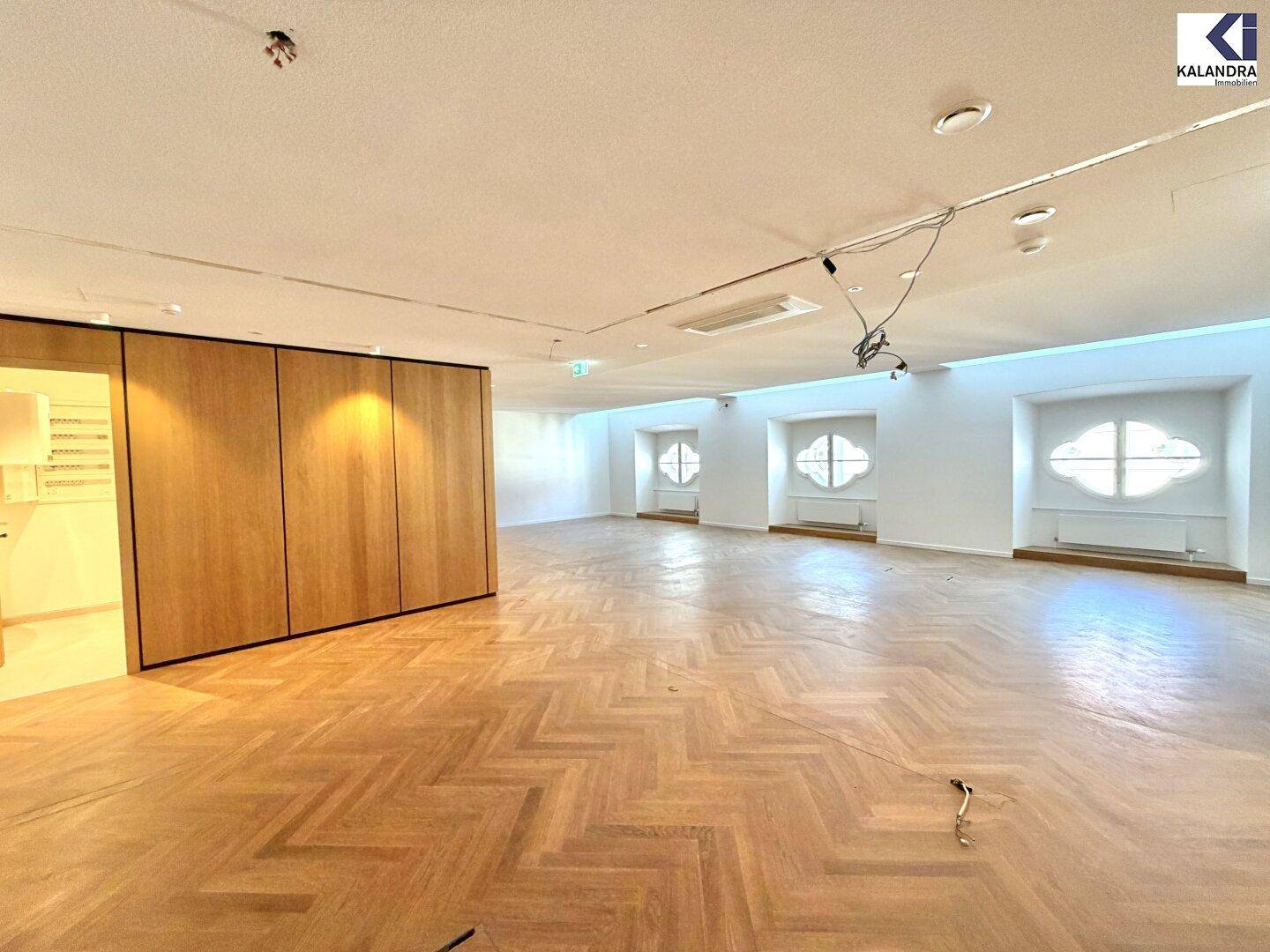 Heller Raum mit Fischgrätparkett und einer eleganten Holzvertäfelung, die einen modernen Akzent setzt.