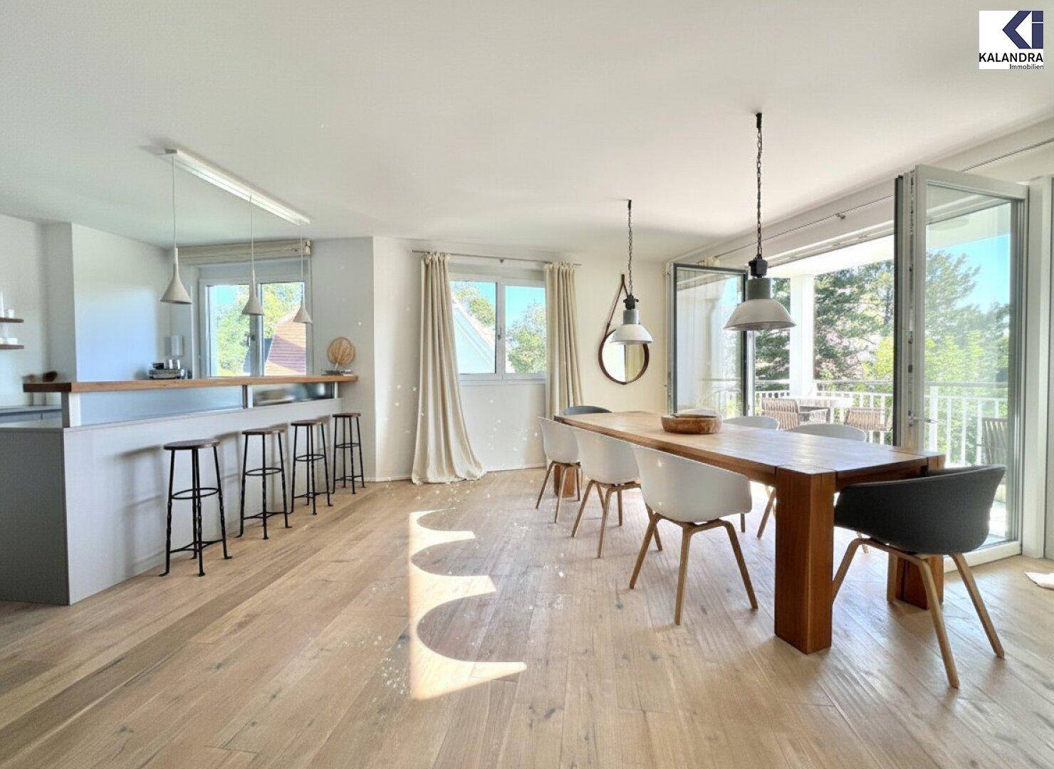 Heller offener Wohn- und Essbereich mit Holzboden und Zugang zum Balkon.