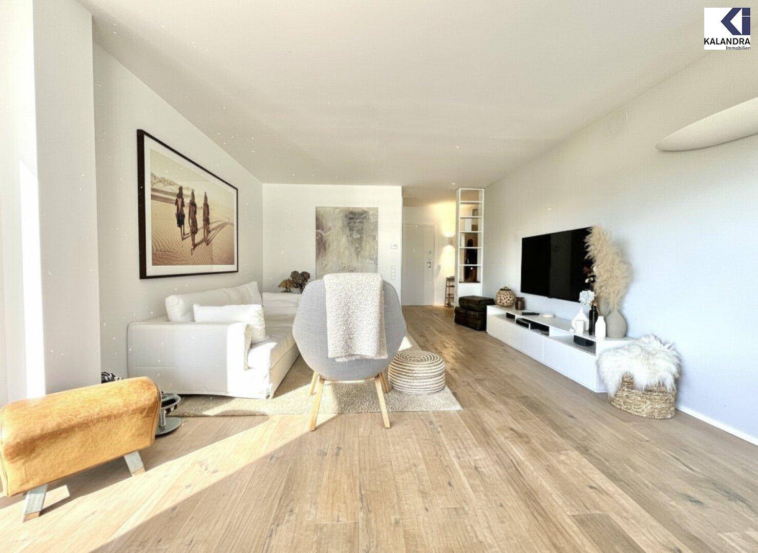 Gemütliches Wohnzimmer mit hellem Holzboden, moderner Einrichtung und großem Fernseher.