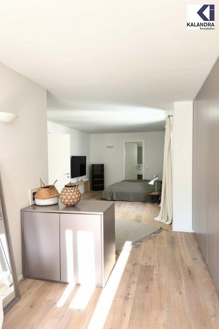 Geräumiges Schlafzimmer mit Holzboden, minimalistischer Einrichtung und viel Tageslicht.