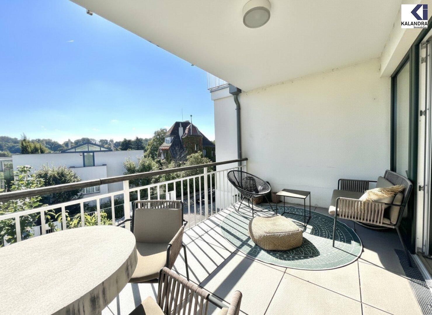 Sonniger Balkon mit bequemen Sitzgelegenheiten und Blick auf die umliegende Bebauung.
