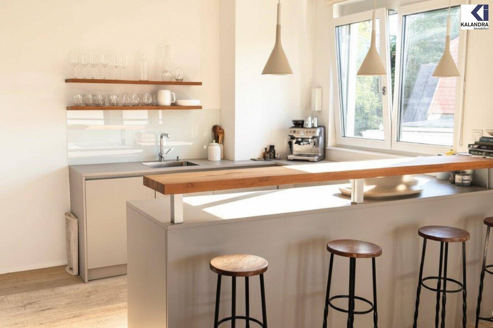 Moderne Küche mit Frühstücksbar, Holztheke und viel Tageslicht durch das Fenster.