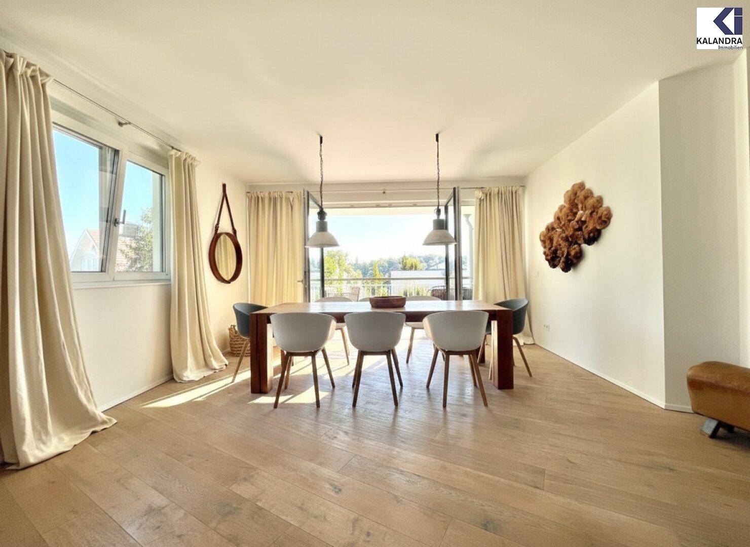 Heller Essbereich mit großem Holztisch, modernen Stühlen und Balkonzugang.