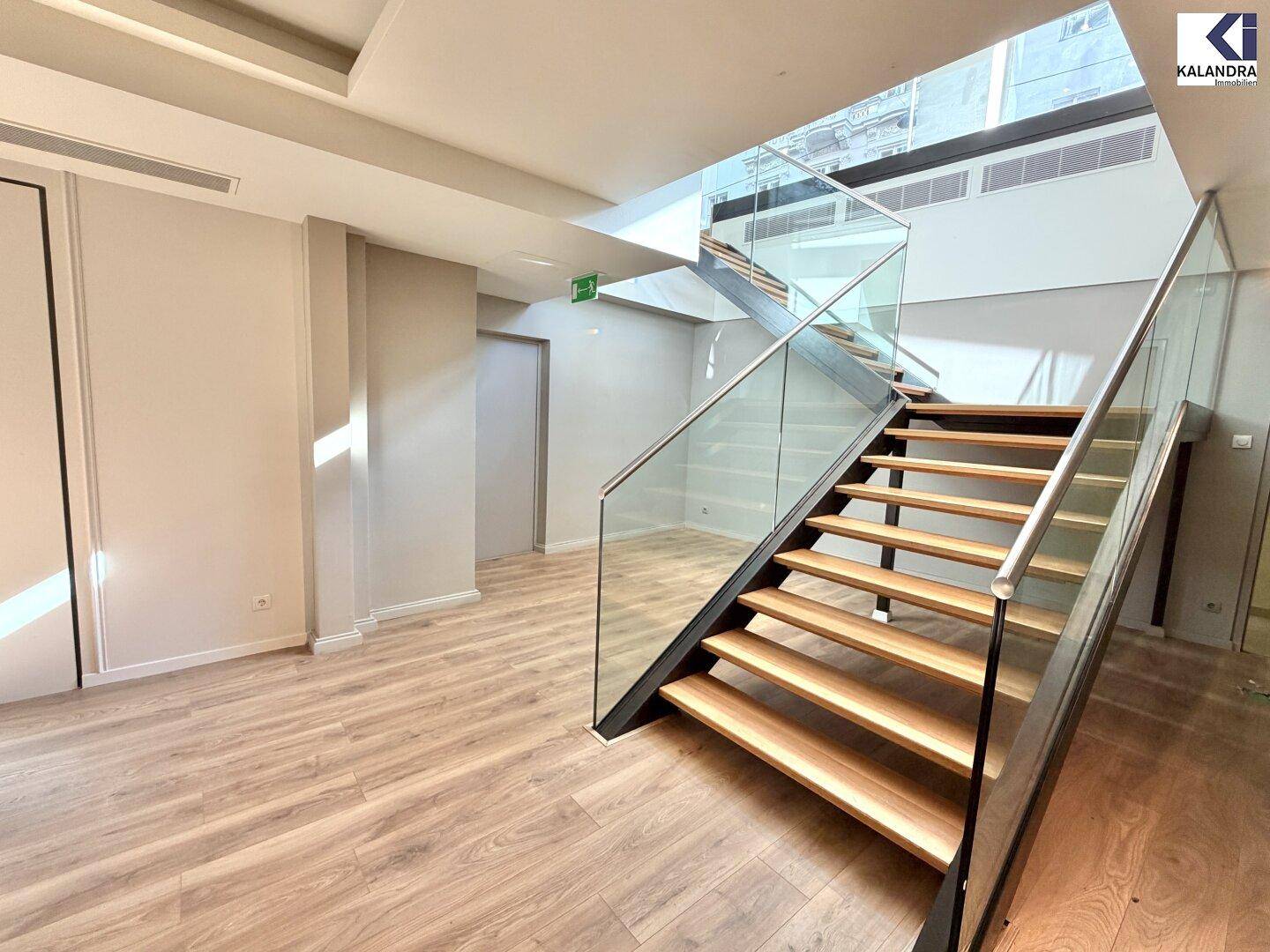 Elegante Holztreppe mit Glasgeländer verbindet die Ebenen dieses modernen Geschäftsraums, hell und offen.
