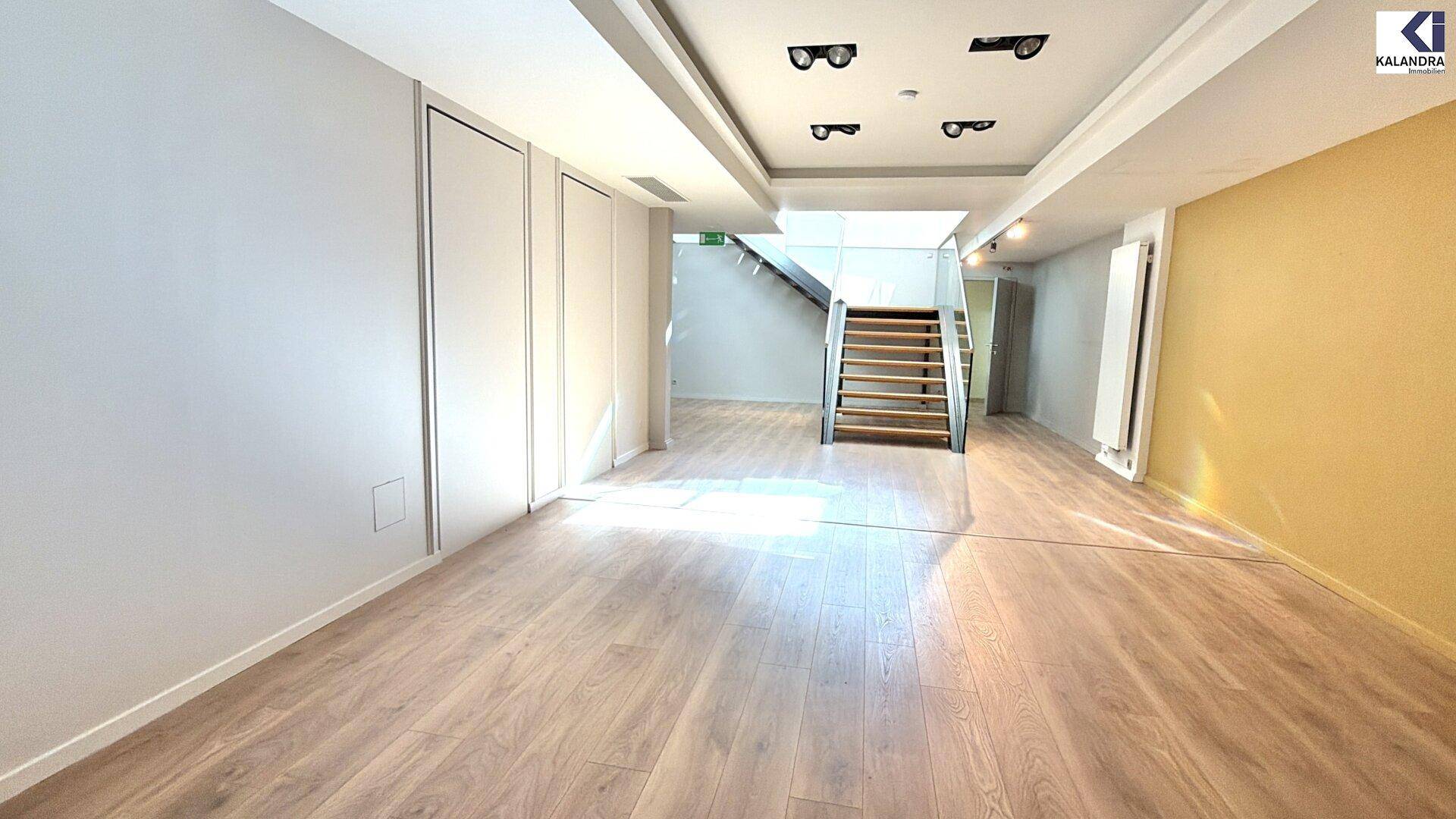 Geräumiger Untergeschossbereich mit hellem Holzfußboden und einer auffälligen gelben Wand, gut beleuchtet.