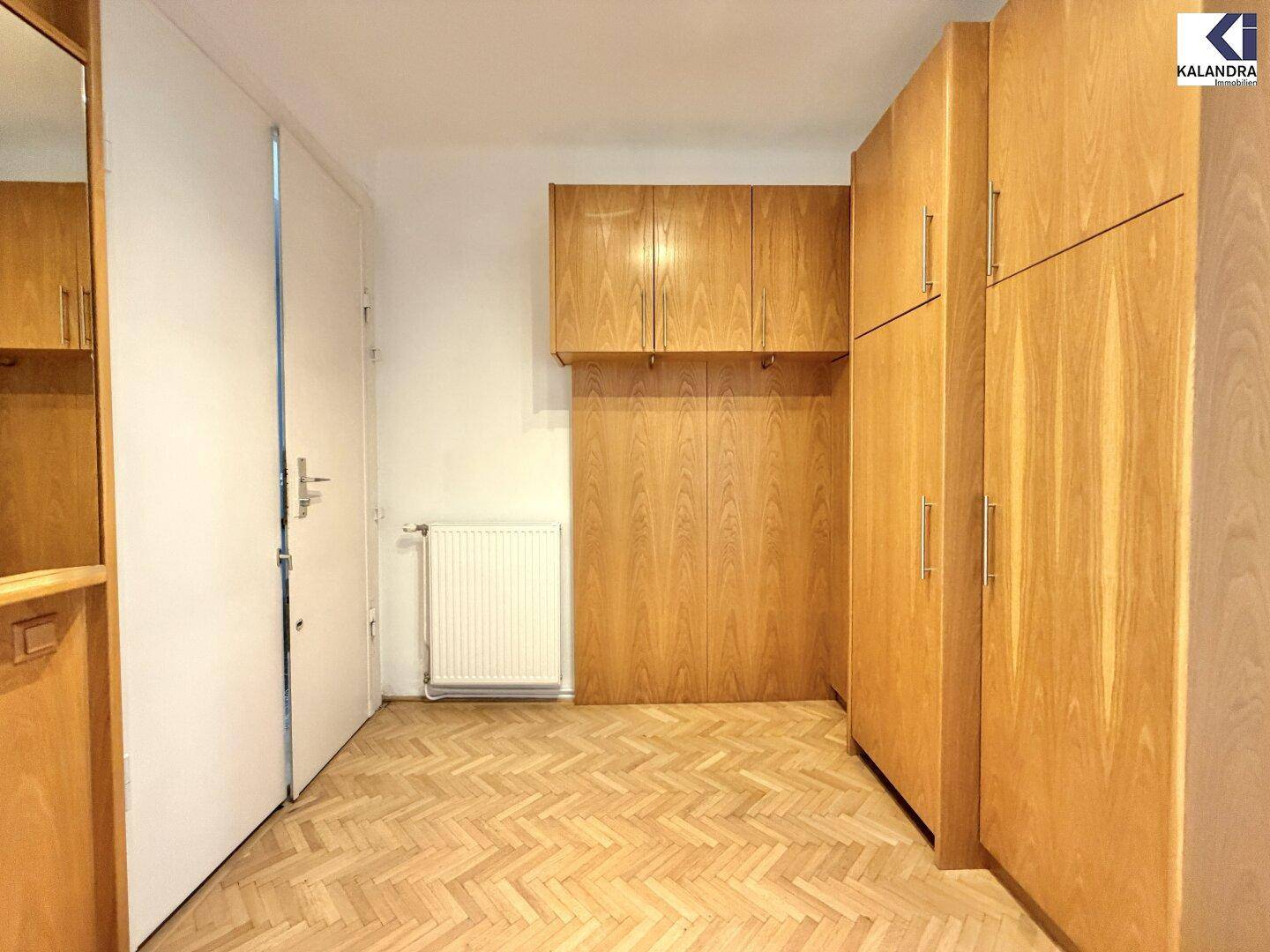 Eingangsbereich oder Flur mit Holzschränken und Fischgrätparkett, bietet praktischen Stauraum.