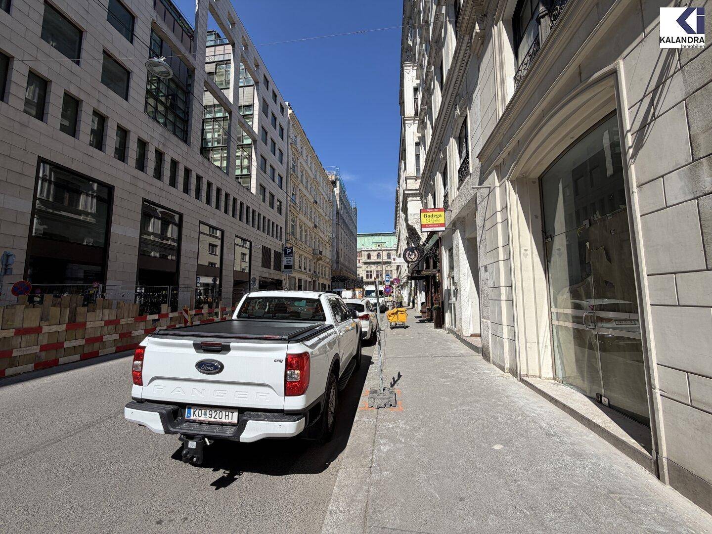 Blick auf eine belebte Stadtstraße mit hohen Gebäuden und einem geparkten weißen Pickup-Truck.