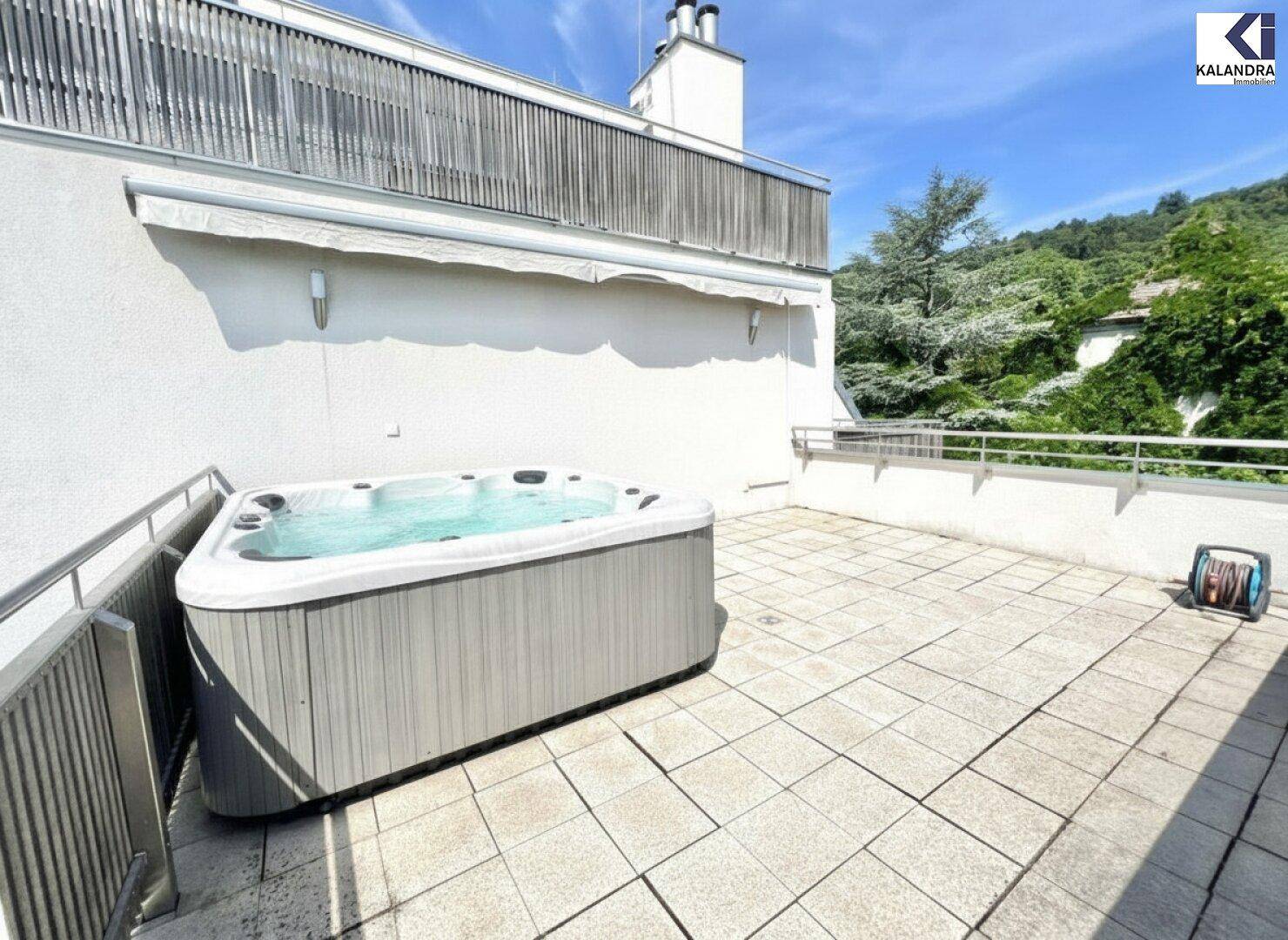 Große Terrasse mit Whirlpool und Blick auf die bewaldeten Hügel.