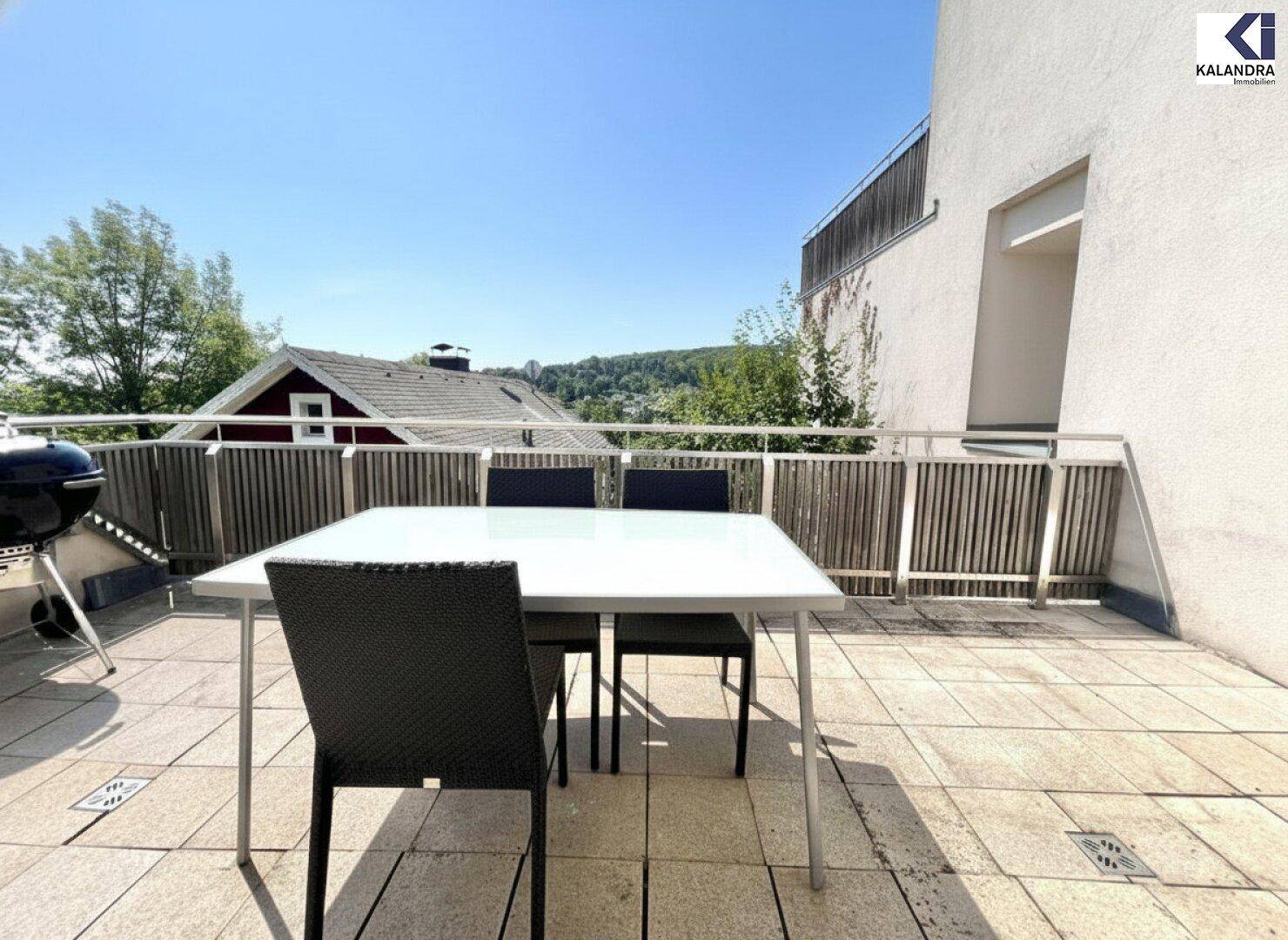 Sonniger Terrassenbereich mit Esstisch und Grill, ideal für Mahlzeiten im Freien.