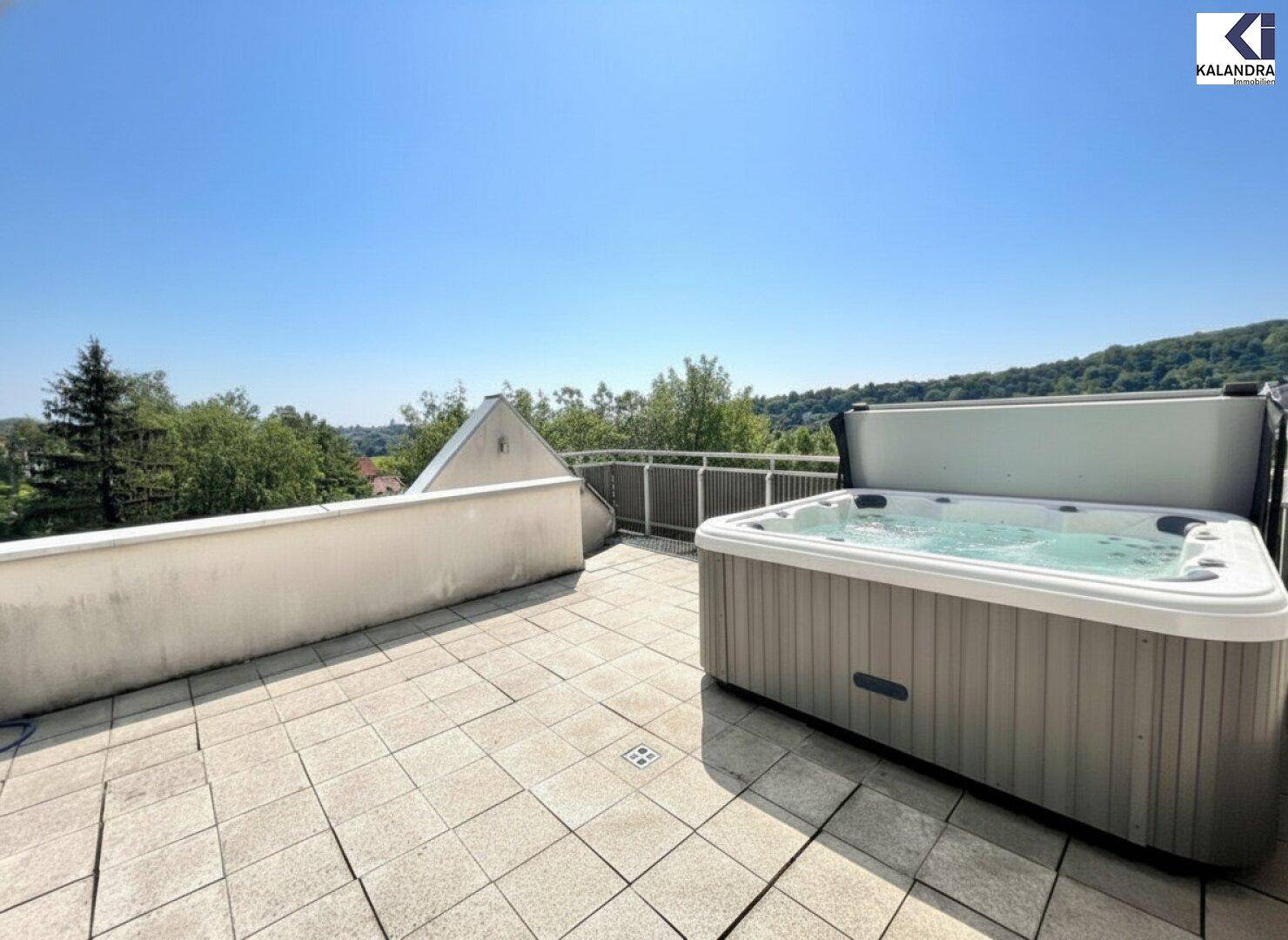 Entspannungsbereich auf der Terrasse mit Whirlpool und sonnigem Ausblick.