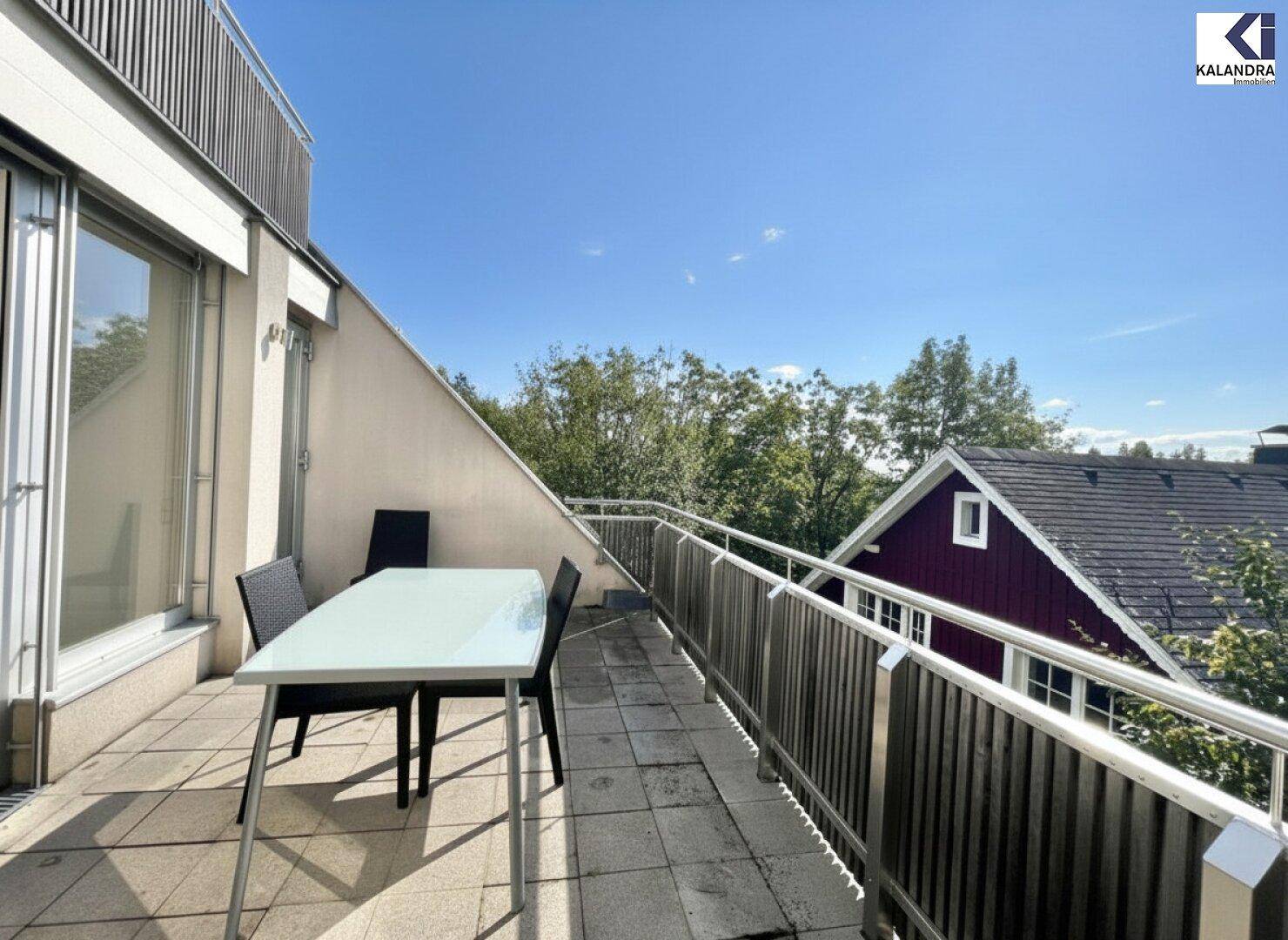 Heller Terrassenbereich mit Esstisch und Stühlen, umgeben von viel Grün.