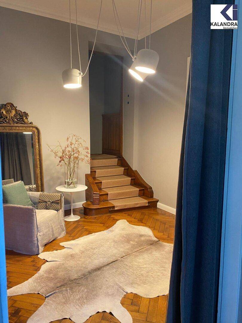 Eingangsbereich mit Holztreppe, Teppichläufer und einem großen Spiegel an der Wand.