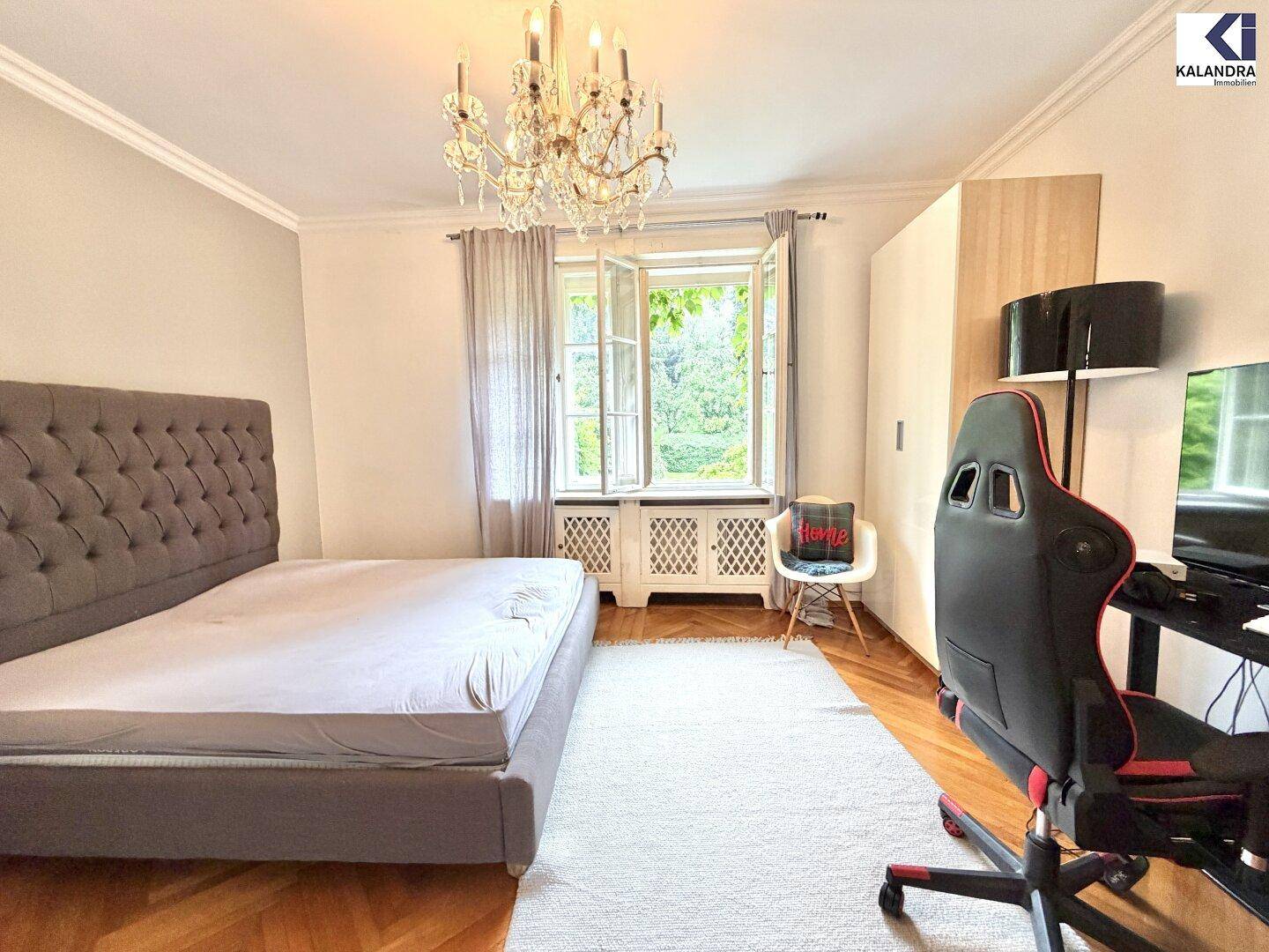 Modernes Schlafzimmer mit Parkettboden, großem Bett und Blick in den grünen Garten.