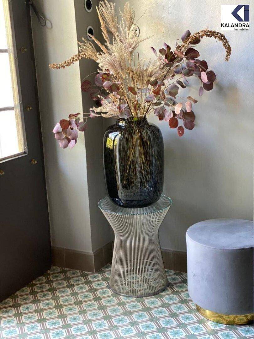 Stilvoller Eingangsbereich mit gemusterten Fliesen, dekorativer Vase und modernem Hocker.
