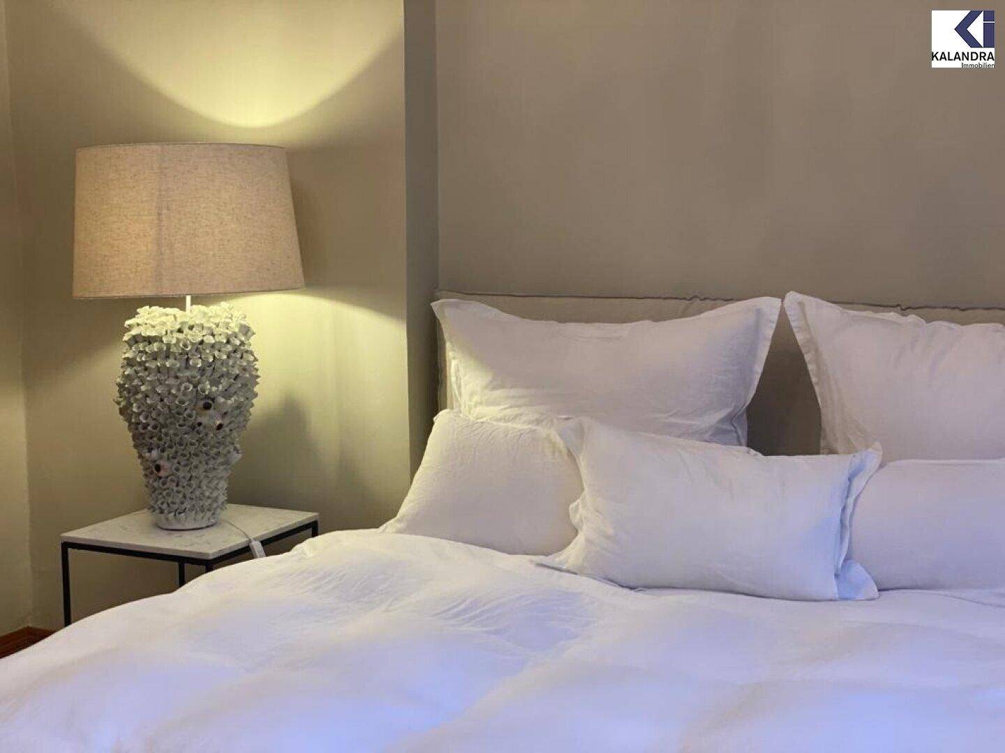 Gemütliches Schlafzimmer mit weißer Bettwäsche und einer dekorativen Nachttischlampe.