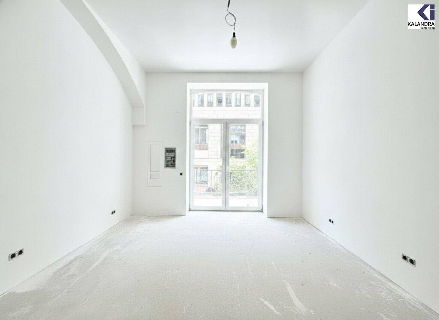 Leerer Raum mit weißen Wänden und einem großen Fenster, das viel Tageslicht hereinlässt.