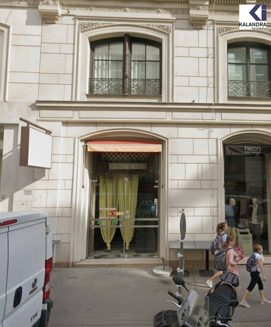 Nahaufnahme einer Ladenfassade mit gelber Markise und Vorhängen, Passanten gehen auf dem Bürgersteig vorbei.