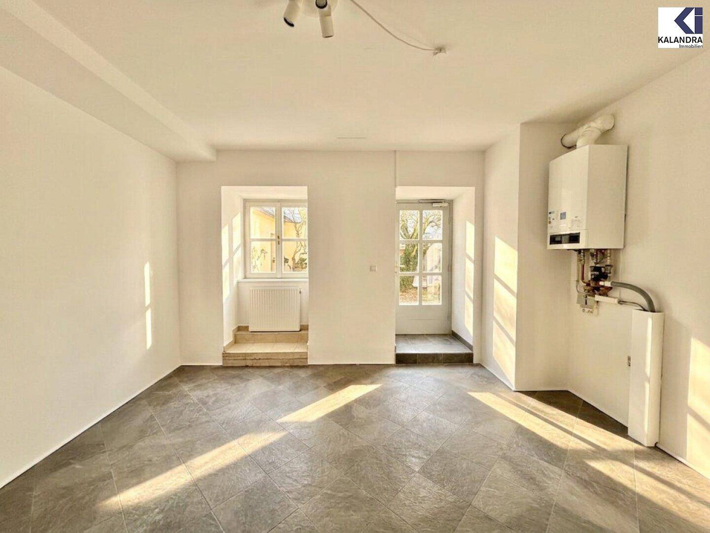 Gewerberaum mit Heizungsanlage an der Wand, großen Fenstern und einem Eingangsbereich.