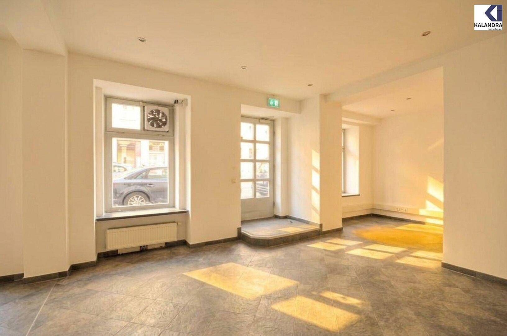 Heller Gewerberaum mit großen Fenstern, Abluftventilator und viel Tageslicht von der Straße.