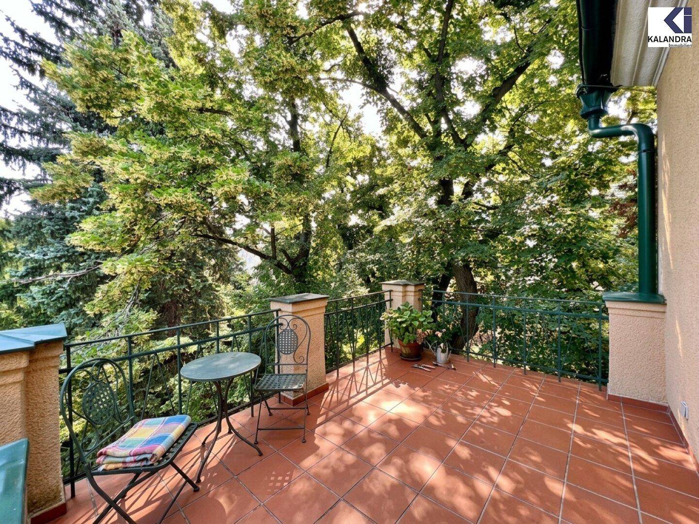 Idyllischer Balkon mit Blick auf üppiges Grün und alte Bäume, ideal für entspannte Stunden im Freien.
