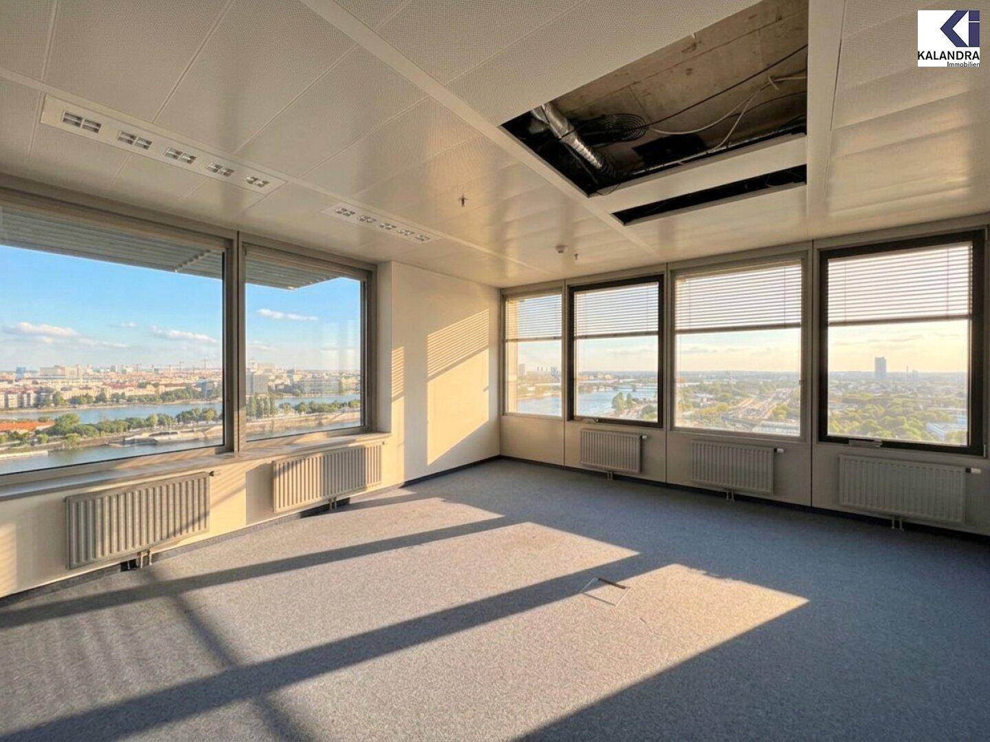 Helles Büro mit Teppichboden und Panoramablick auf die Stadt, wobei ein Teil der Decke für Wartungsarbeiten geöffnet ist.