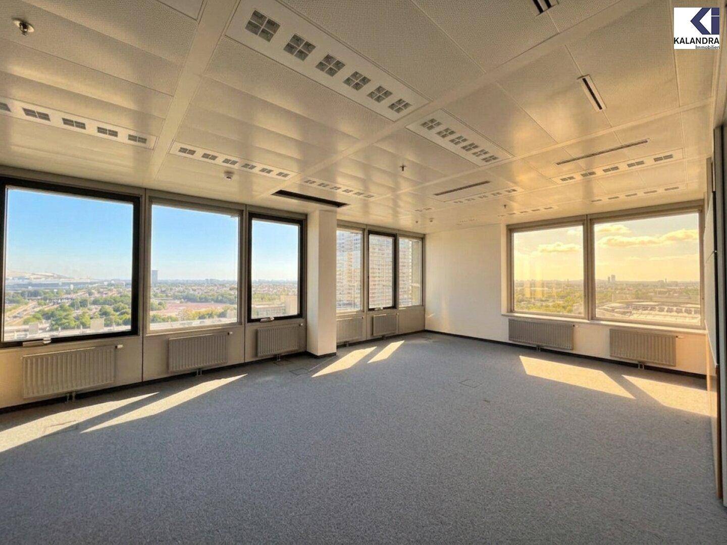 Großes, leeres Büro mit Teppichboden und weitem Blick auf die Stadt durch die zahlreichen Fenster, ideal für Büronutzung.