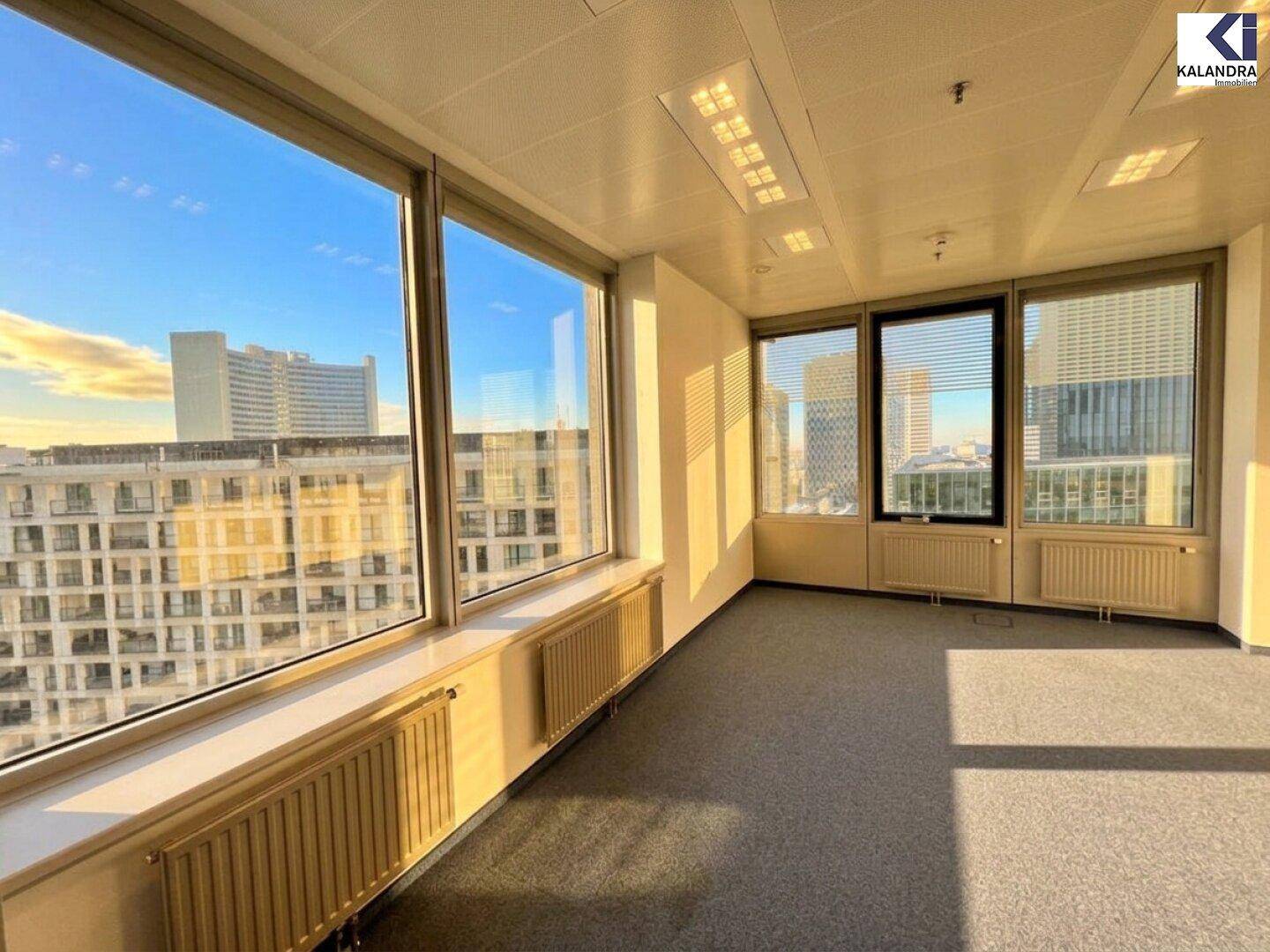Büro mit großen Fenstern, die einen direkten Blick auf moderne Gebäude und die städtische Umgebung bieten.