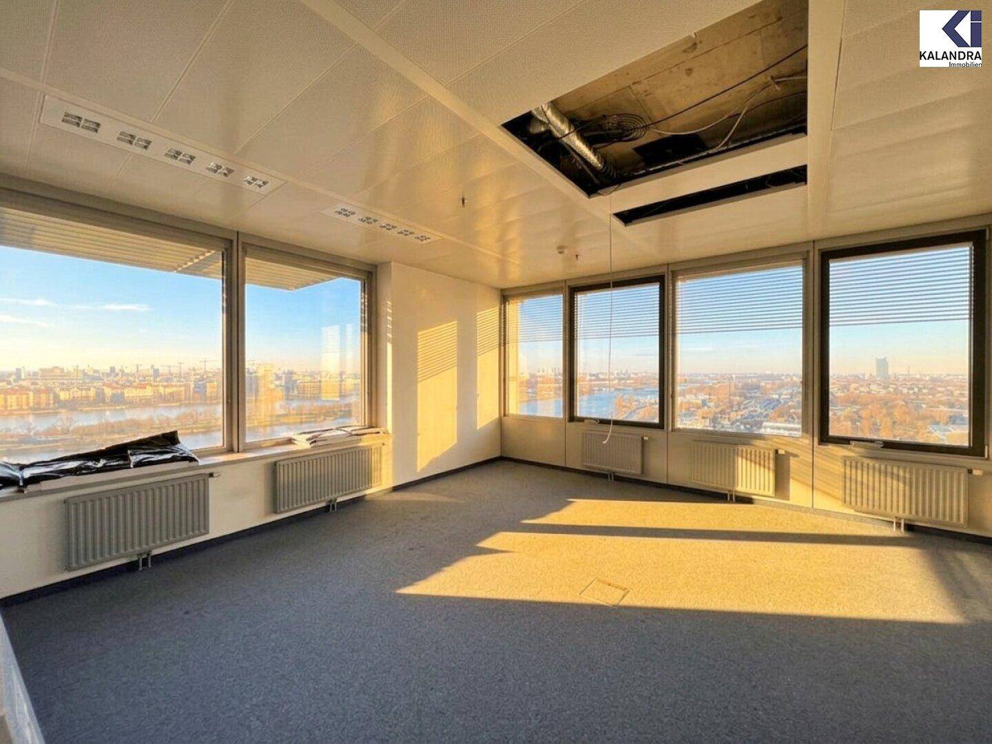 Bürofläche mit Teppichboden und weitem Blick über die Stadt und den Fluss, teilweise mit offener Decke.