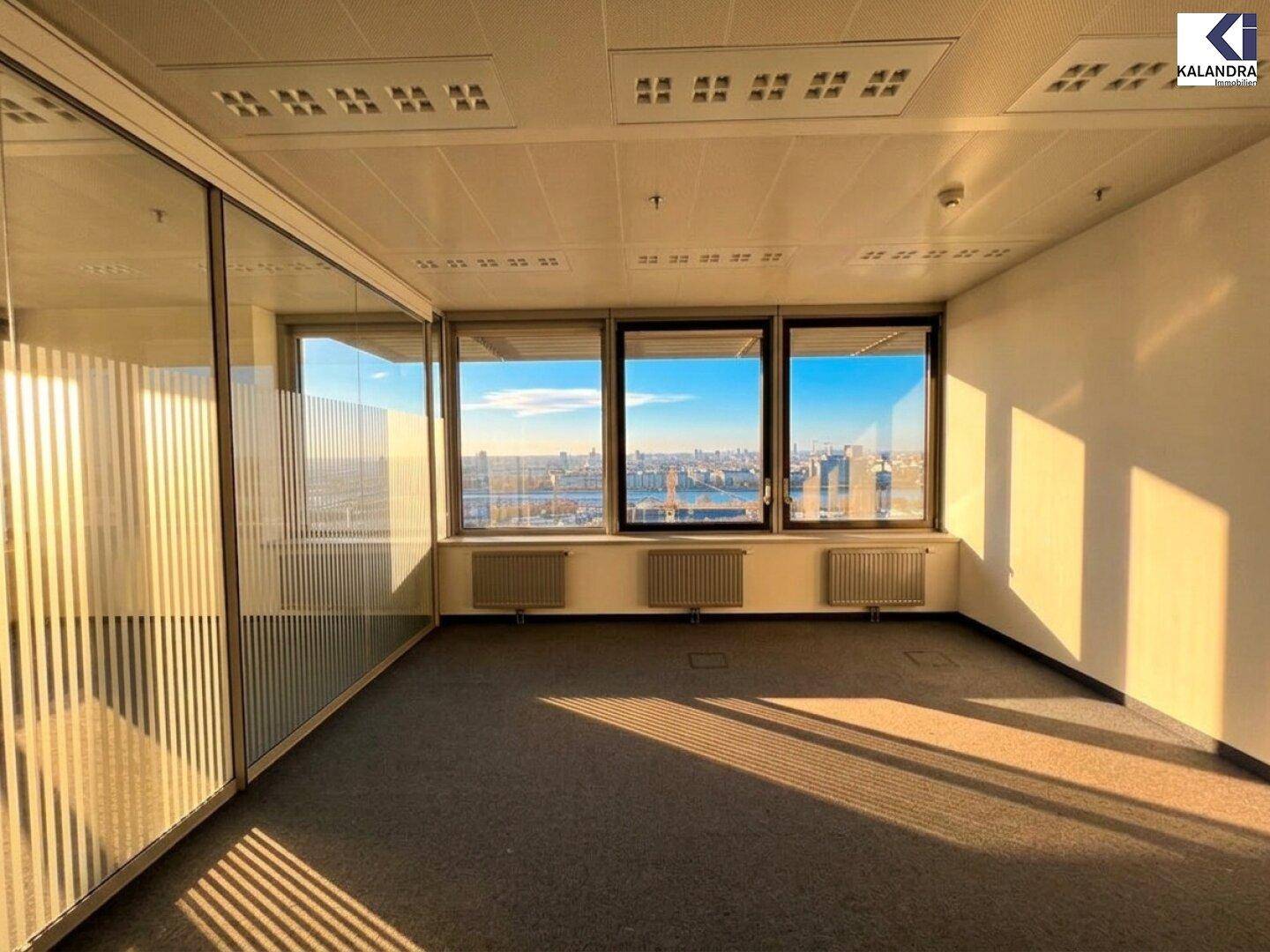 Büro mit Glaswänden und großen Fenstern, die viel Licht und eine weite Aussicht auf die Stadt bieten.