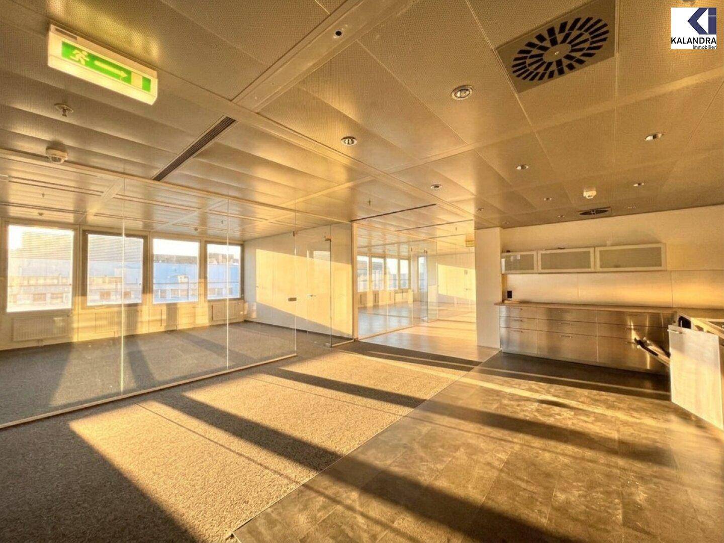 Büro mit Teppich- und Betonboden, Glaswänden und Einbauschränken, bietet flexible Arbeitsbereiche.