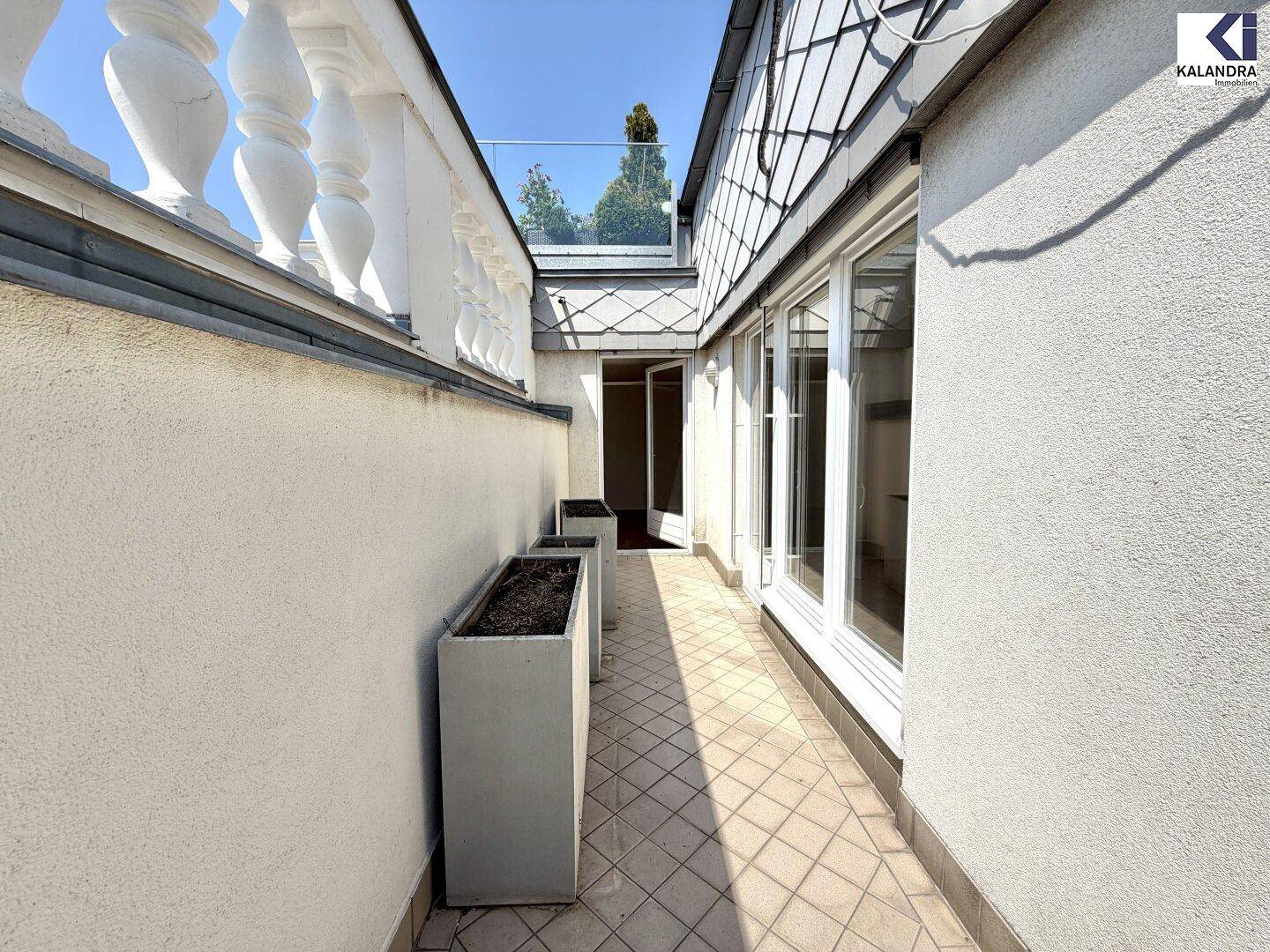 Schmaler Balkon mit Fliesenboden und Pflanzkübeln, der einen ruhigen Außenbereich bietet.