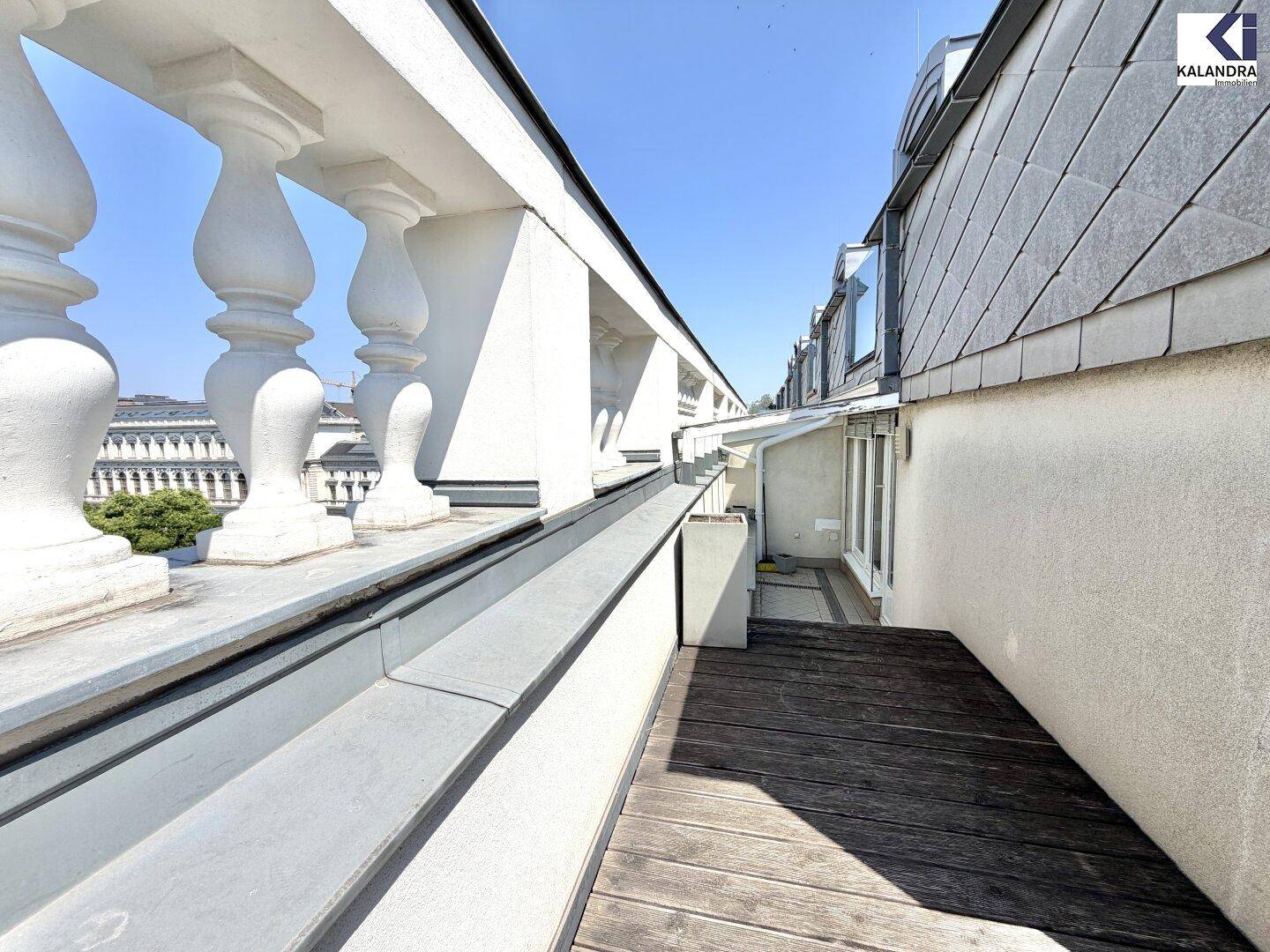 Lange Dachterrasse mit klassischer Balustrade und Holzboden, die einen weiten Blick bietet.