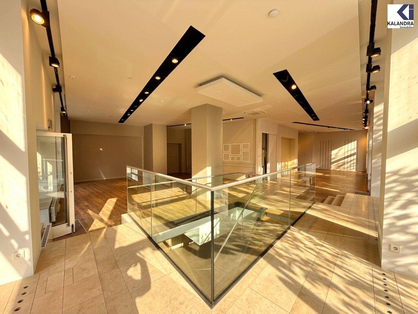 Offener Verkaufsbereich mit eleganter Glasbrüstung und Treppe, die zu einer weiteren Ebene führt.