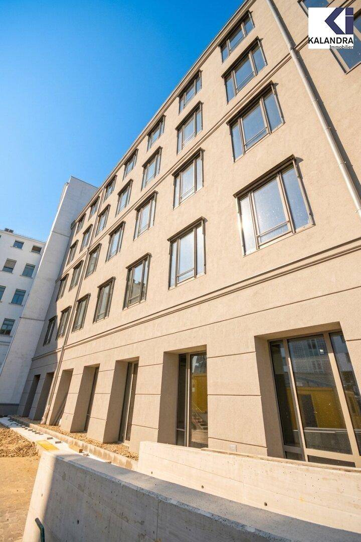 Moderne Gebäudefassade mit vielen Fenstern und klaren Linien unter blauem Himmel.