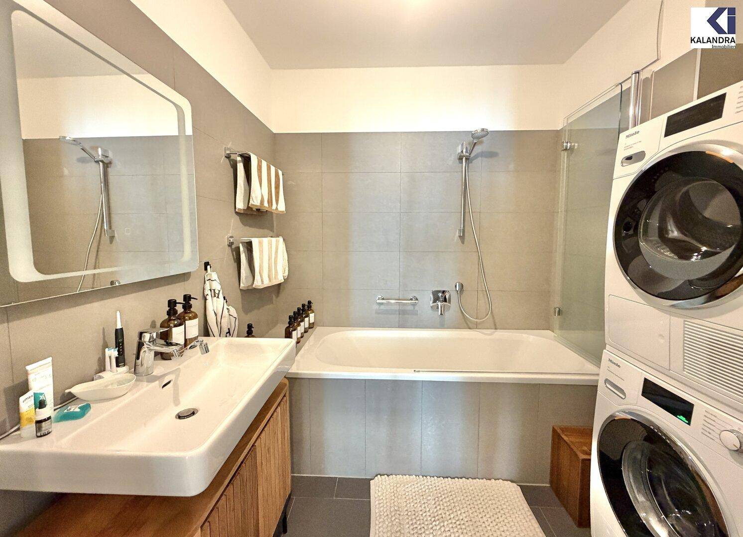 Modernes Badezimmer mit Badewanne, Dusche, Einzelwaschbecken und Waschmaschinenanschluss.
