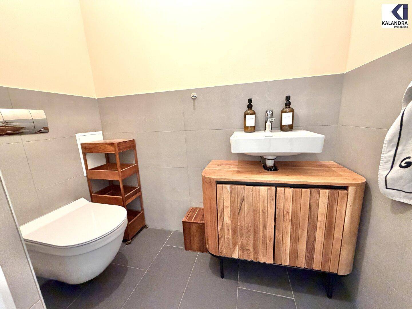 Gäste-WC mit wandhängendem WC, kleinem Waschbecken und Holzunterschrank.