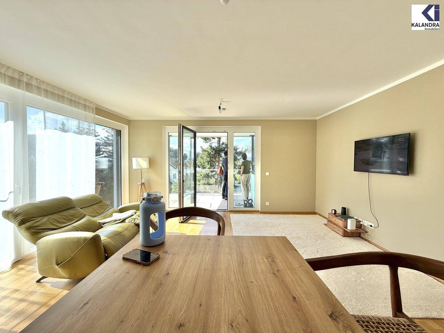 Helles Wohnzimmer mit Esstisch, bequemer Couch und großem Zugang zum Balkon.