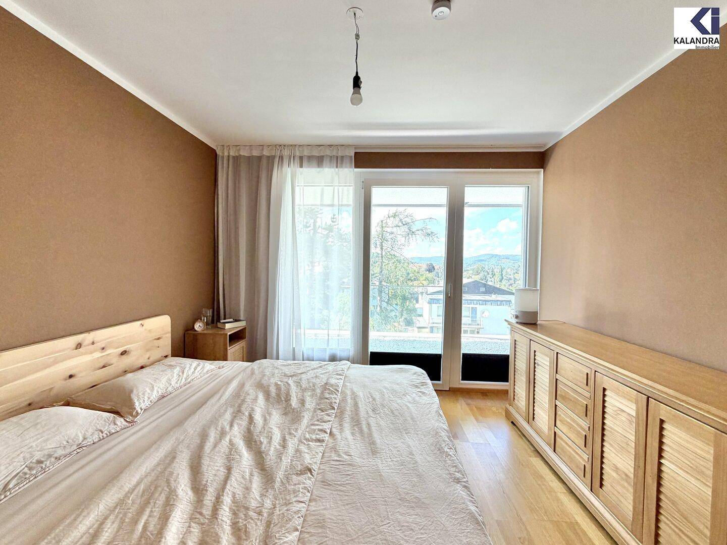 Gemütliches Schlafzimmer mit Holzbett, Kommode und großem Fenster mit Bergblick.