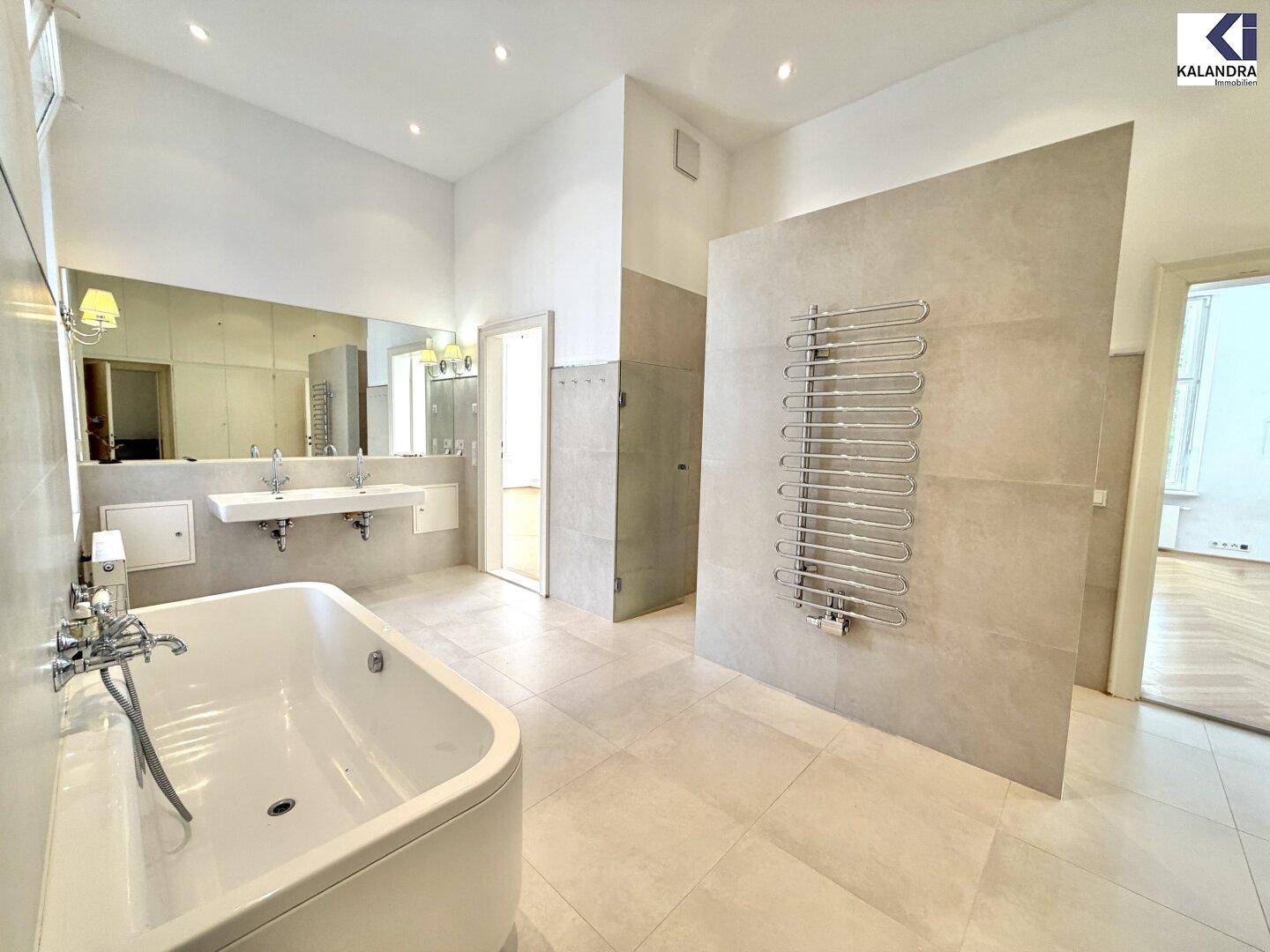 Elegantes Badezimmer mit freistehender Badewanne, Doppelwaschbecken und beheiztem Handtuchhalter.