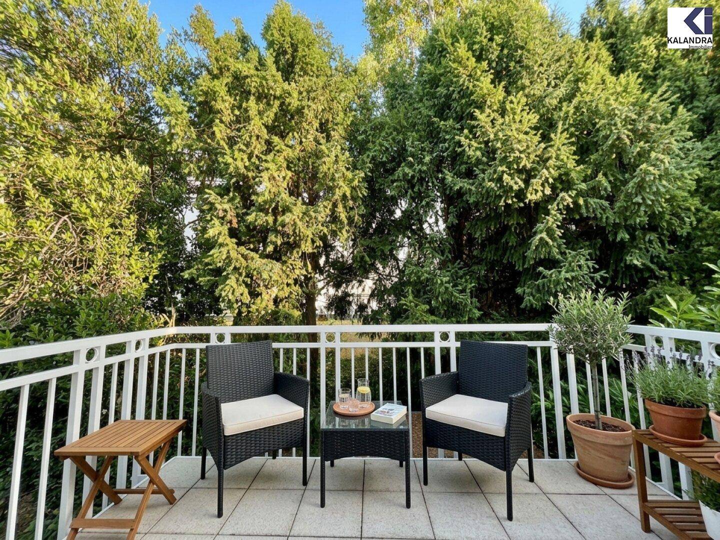 Gemütlicher Balkon mit Sitzgelegenheiten und Blick auf grüne Bäume.