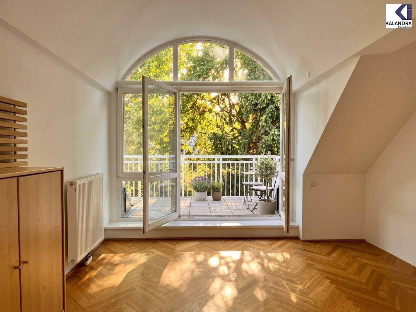 Heller Raum mit beeindruckendem Rundbogenfenster und direktem Zugang zu einem Balkon.